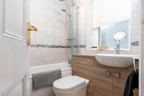 a bathroom with a toilet and a sink and a mirror at Sandbanks in Deganwy