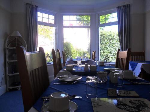 a dining room with a table with a blue table cloth at Cleave Court Guest House in Llandudno