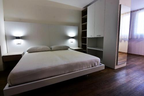 a bedroom with a bed with two lamps and a mirror at Appartamenti CIMA LASTE in Mezzana