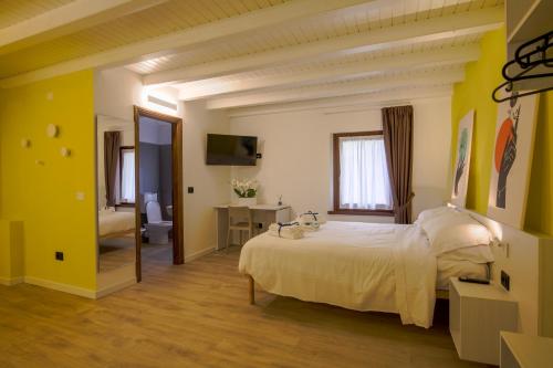 a bedroom with a white bed and a bathroom at Le Tofane, vivi la bellezza di Belluno - Primula in Sòis