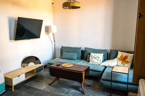a living room with a blue couch and a tv at Villa Covadonga by beBalmy in Pedruño