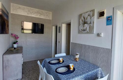 een eetkamer met een tafel met borden en een televisie bij Appartamenti Da Michela in Cavallino-Treporti