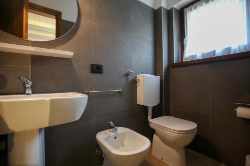a bathroom with a sink and a toilet and a mirror at Appartamento immerso nella natura con parcheggio - Stella Alpina in Sòis