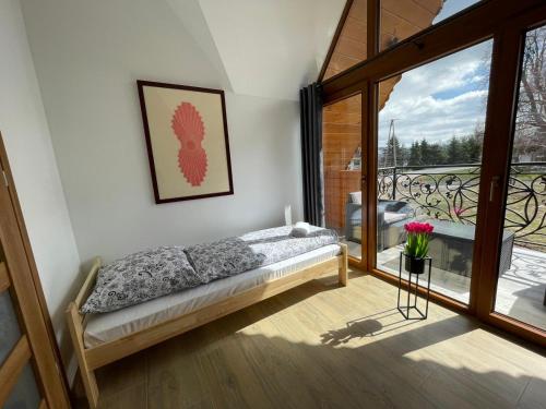 a bedroom with a bed and a balcony at Stylove Domki Bańska Niżna Domki z Jacuzzi in Bańska Niżna