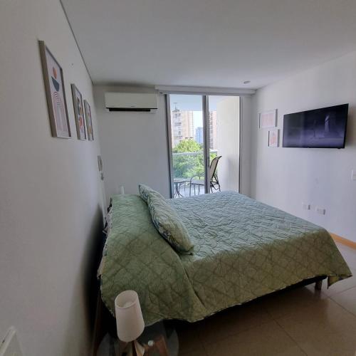 Un dormitorio con una cama con una manta verde y una ventana. en Torres del Mar Santa Marta, en Santa Marta