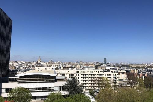 un grand bâtiment blanc avec une ville en arrière-plan dans l'établissement Spacious and modern nest with a view on Paris, à Paris