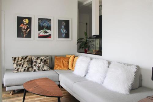 - un salon avec un canapé gris et des oreillers dans l'établissement Spacious and modern nest with a view on Paris, à Paris