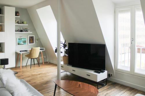 un salon avec une télévision à écran plat sur une table dans l'établissement Spacious and modern nest with a view on Paris, à Paris