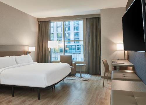 una camera d'albergo con un grande letto bianco e una scrivania di AC Hotel Nashville Downtown a Nashville