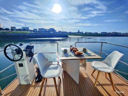 una mesa y sillas en un barco en el agua en Floating Experience - Casa flutuante a 25 min do Porto en Póvoa de Varzim