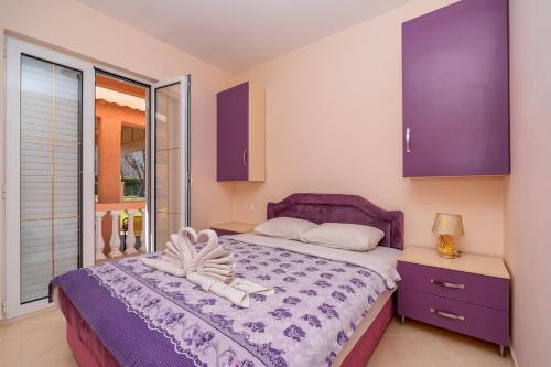 a bedroom with a purple bed and a window at Apartmani Milacic in Sutomore