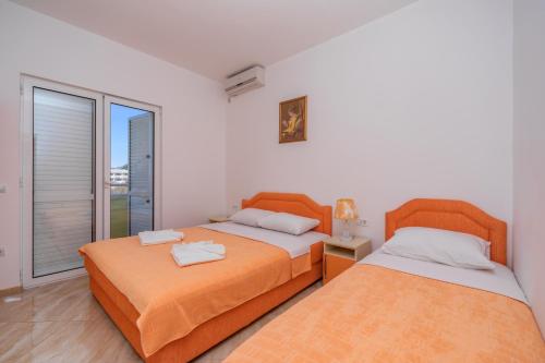 1 dormitorio con 2 camas y ventana en Apartmani Milacic, en Sutomore
