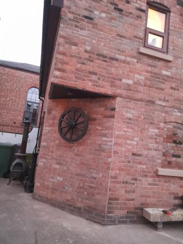 a brick wall with a wheel on the side of a building at Willow's Cottage in Edwinstowe