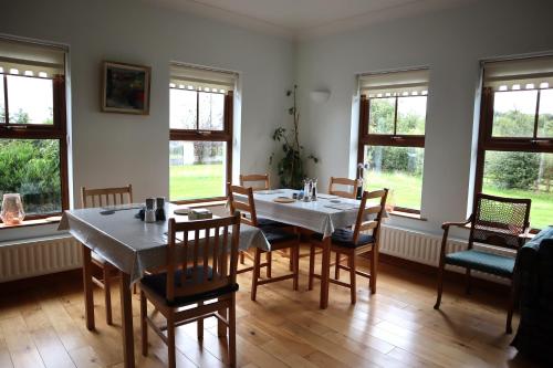 a dining room with a table and chairs and windows at The White House in Enniskillen