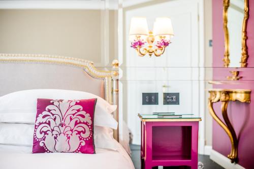 a pink and white bedroom with a bed and a table at Hotel Villa e Palazzo Aminta in Stresa