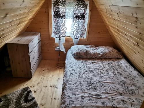 sypialnia na poddaszu z łóżkiem i oknem w obiekcie Domki nad Narwią w mieście Dzierzenin