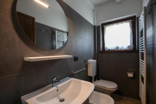 a bathroom with a sink and a mirror and a toilet at Appartamento immerso nella natura con parcheggio - Viola in Sòis