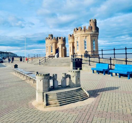 a castle with blue benches in front of it at Charming 2 Bedroom Holiday Chalet in Withernsea