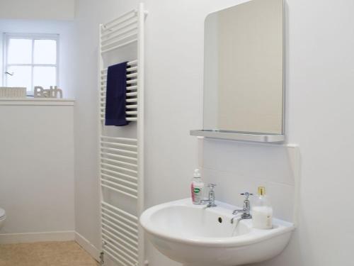 a white bathroom with a sink and a mirror at Key House in Falkland