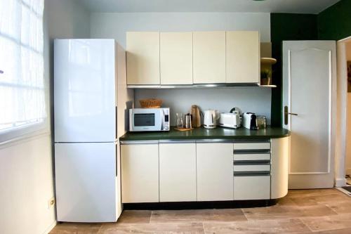 eine Küche mit einem weißen Kühlschrank und einer Mikrowelle in der Unterkunft Appartement avec vue sur la tour de Vésone in Périgueux