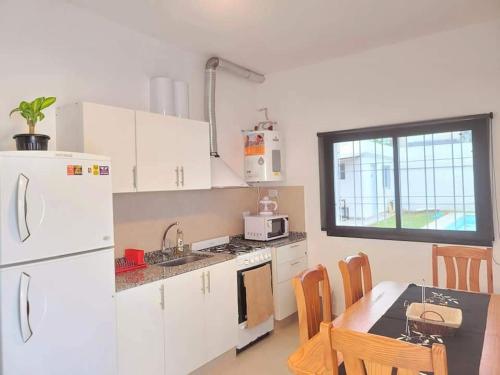 a kitchen with a white refrigerator and a table with chairs at Casa Roque Funes, ubicado en Cerro de las Rosas Córdoba, Ofrece, Asador, Pileta, Cercanias, Estadio Kempes, aeropuerto Ambrosio Taravella, Orfeo Superdomo, Córdoba Shopping Mall, Sanatorio Allende, INCLUYE IMPUESTOS Y CARGOS in Cordoba