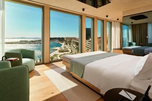 a bedroom with a large bed and large windows at Hotel Ambasador in Split