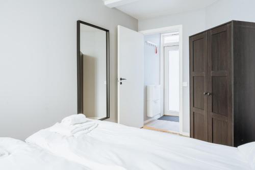 - une chambre avec un lit blanc et un miroir dans l'établissement Stay Strandgaten - New apartment in city center, à Bergen