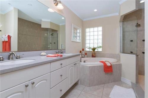 een badkamer met een wastafel, een bad en een douche bij A Touch of Modern with Views Condo in Manasota Key