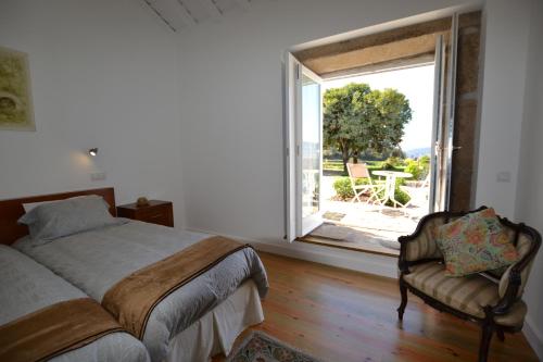 - une chambre avec un lit, une fenêtre et une chaise dans l'établissement Casa de Cartemil, à Ponte de Lima