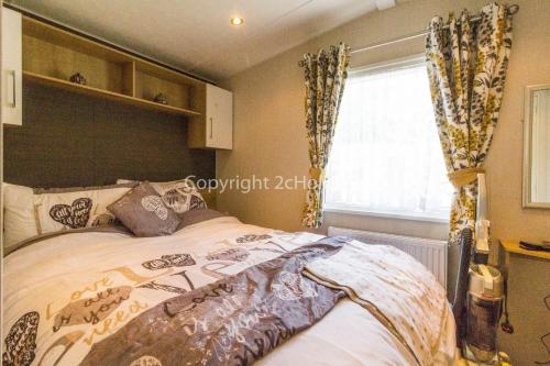 洛斯托夫特的住宿－Brilliant Caravan With A Partial Sea View In Suffolk Ref 32026az，一间卧室设有一张大床和一个窗户。