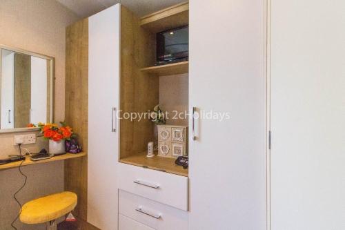 a kitchen with a white cabinet and a stool at Brilliant Caravan With A Partial Sea View In Suffolk Ref 32026az in Lowestoft