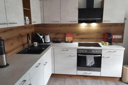 a kitchen with white cabinets and a sink and an oven at Wellness Ferienwohnung Biene im Bergischen Land in Much