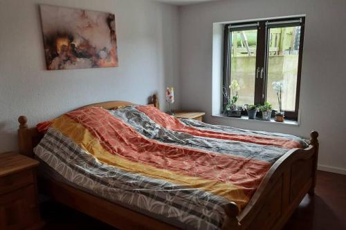 a bed with a blanket on it in a bedroom at Wellness Ferienwohnung Biene im Bergischen Land in Much