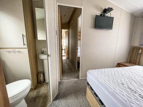 a small bathroom with a bed and a toilet at Beautiful Caravan For Hire With A Partial Sea View In Suffolk Ref 32042az in Lowestoft