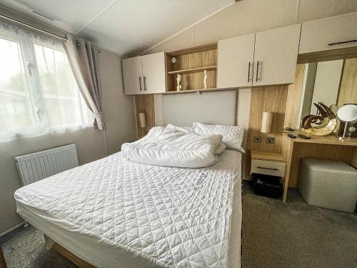a bedroom with a bed with a white comforter at Beautiful Caravan For Hire With A Partial Sea View In Suffolk Ref 32042az in Lowestoft