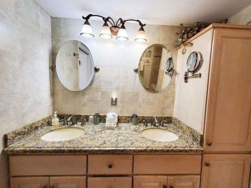 a bathroom with two sinks and two mirrors at Freds Santa Maria Harbour Resort Condo in Fort Myers Beach