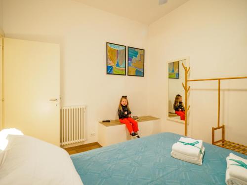Una bambina seduta su un bancone in una camera da letto di Casa Pina Quiet Apartment a Vernazza