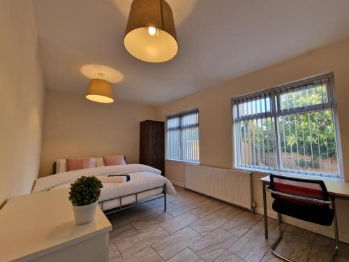 een slaapkamer met een bed, een bureau en 2 ramen bij Nice Living Serviced Accommodations 6 in Birmingham