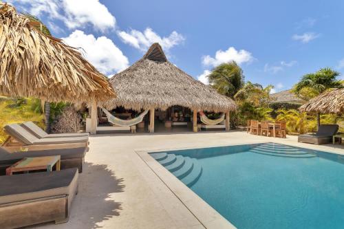 un complejo con una piscina con sillas y sombrillas en Windhoek Resort Bonaire en Kralendijk