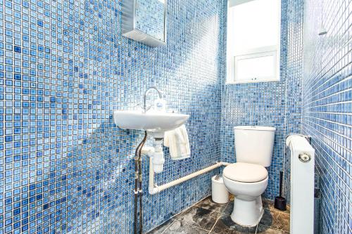 a blue tiled bathroom with a toilet and a sink at The Salt Pot in Ventnor