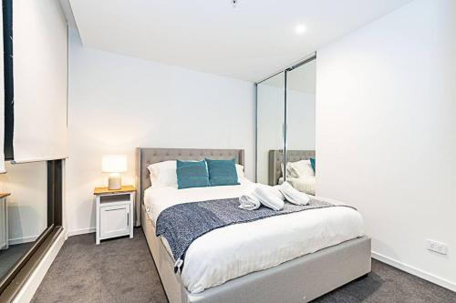 a bedroom with a bed with blue pillows and a mirror at Relaxing Urban Oasis in Melbourne