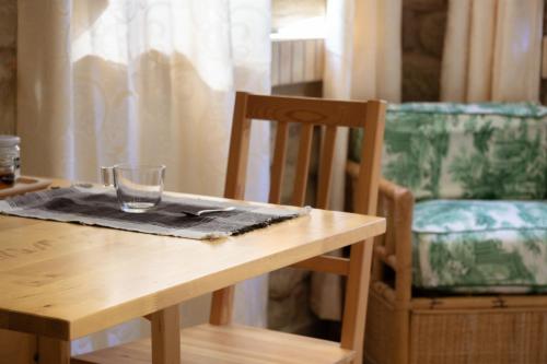a wooden table with a glass on a napkin and a chair at Le Colline di Giulia - Mini Casa ai piedi della collina in Venarotta