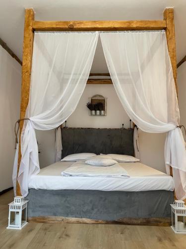 a bedroom with a canopy bed with white drapes at Pensiunea La Popa’s ( Vulcanii Noroioși ) 