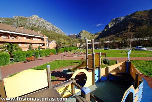 un parque infantil en un parque con montañas al fondo en Angliru 1 Suite, en Castandiello