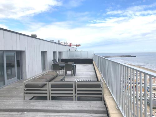 a deck with a table and chairs and the ocean at Holiday Suites Blankenberge in Blankenberge