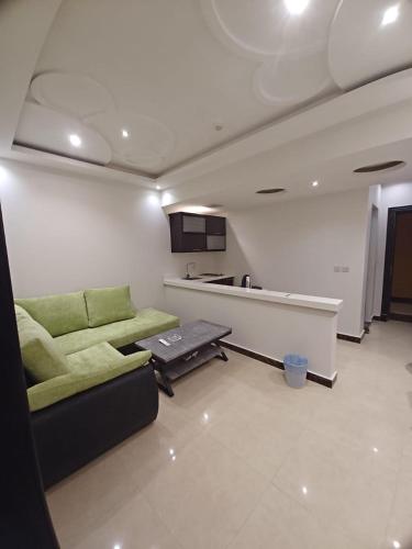 sala de estar con sofá verde y cocina en شقق طلائع الدانه للوحدات السكنية المفروشة, en Riad