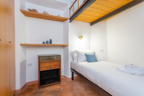 a small bedroom with a bed and a wooden shelf at Barberini 3 BDR Apartment in Rome
