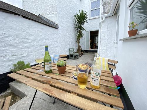 a wooden table with two bottles and glasses of wine at Spacious, seaside, Victorian home "Bay View Terrace", Penzance in Penzance