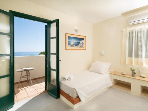 a bedroom with a bed and a view of the ocean at Kalimera Village in Hersonissos