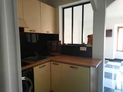 a kitchen with a counter and a sink and some windows at "Magnifique appartement" Vue Mer, Rénové, Plage in Menton